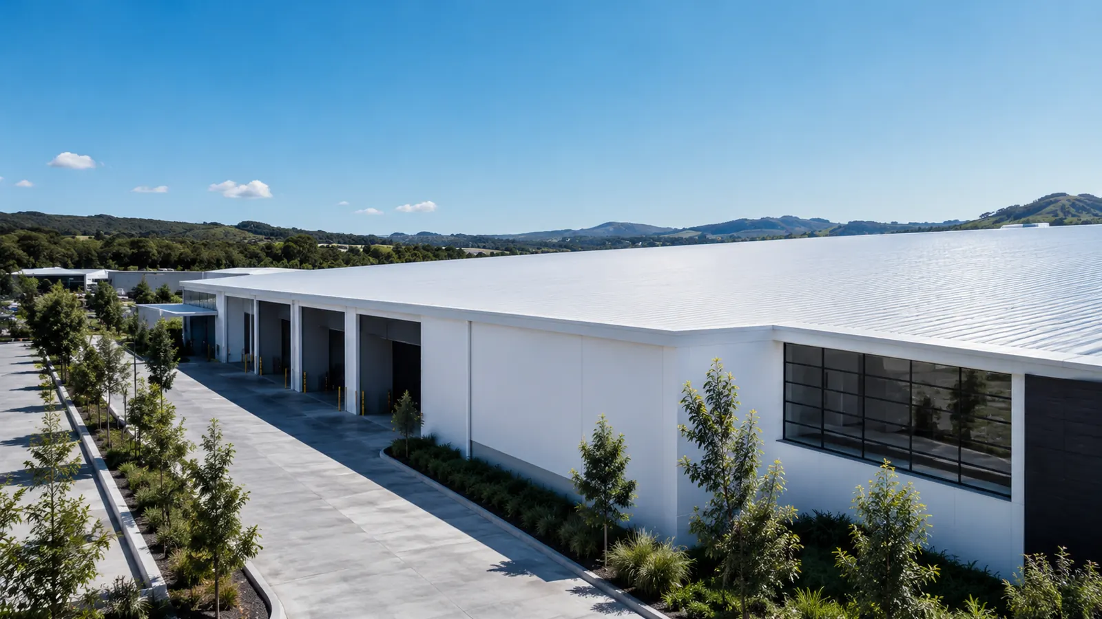 Industrial warehouse building with loading docks and a light-coloured roof, illustrating a NusCoolWall™ application scenario